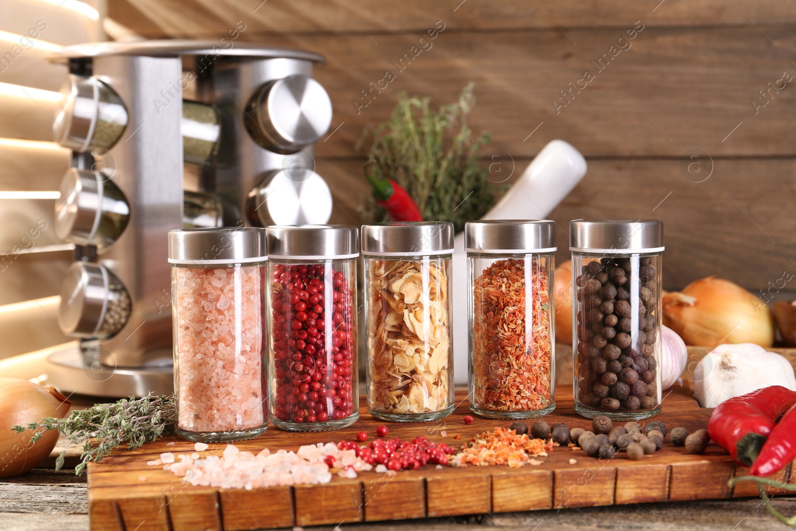 Photo of Different spices in glass jars and on wooden table
