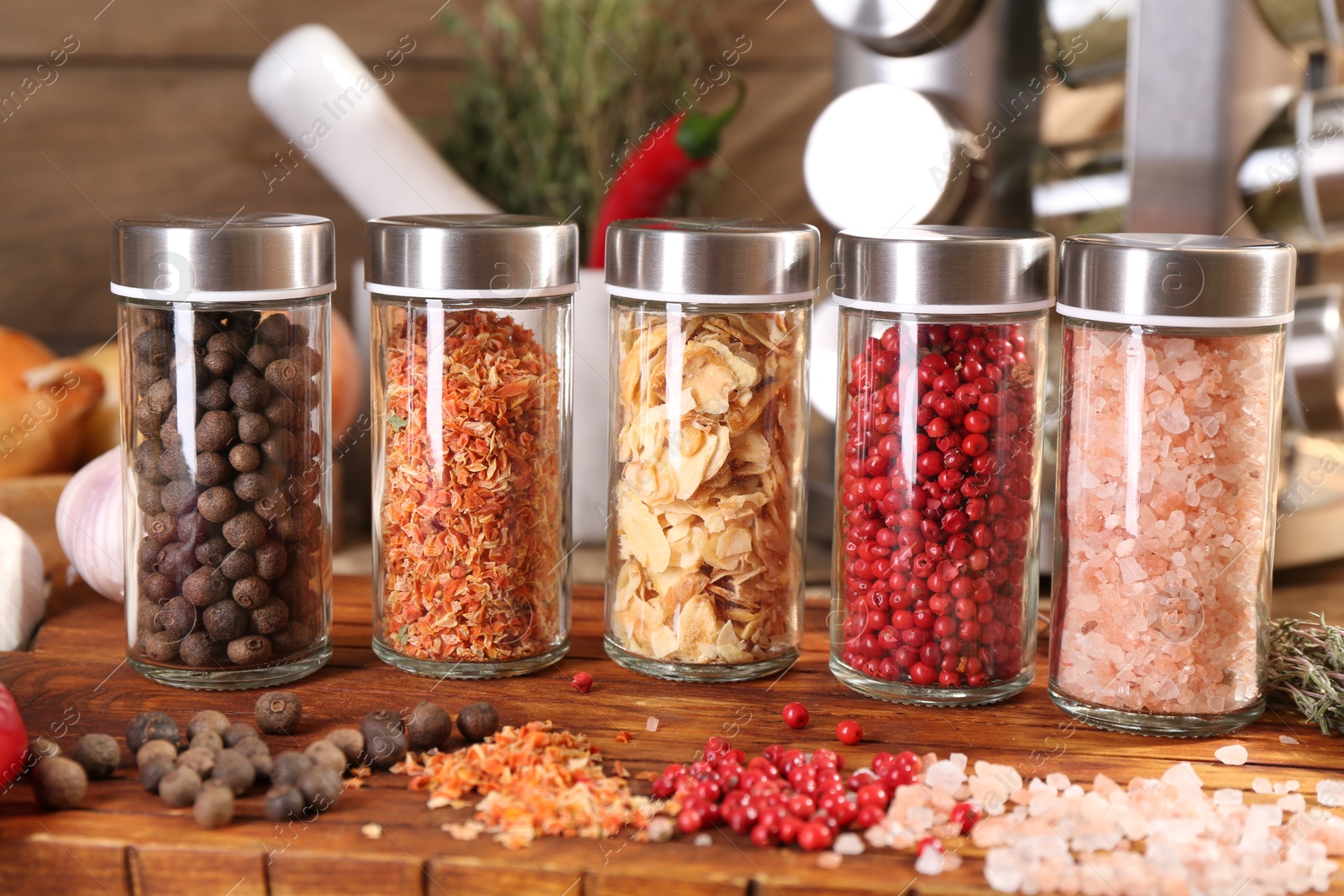 Photo of Different spices and glass jars and on wooden table, closeup
