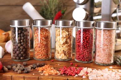 Photo of Different spices and glass jars and on wooden table, closeup