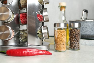 Photo of Set of different spices in glass jars and oil on light grey table in kitchen, closeup