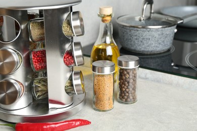 Photo of Set of different spices in glass jars and oil on light grey table in kitchen, closeup