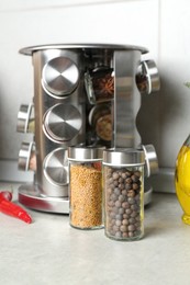 Photo of Set of different spices in glass jars on light grey table in kitchen, closeup