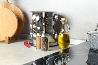 Photo of Set of different spices in glass jars and oil on light grey table in kitchen