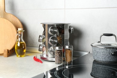 Photo of Set of different spices in glass jars and oil on light grey table in kitchen