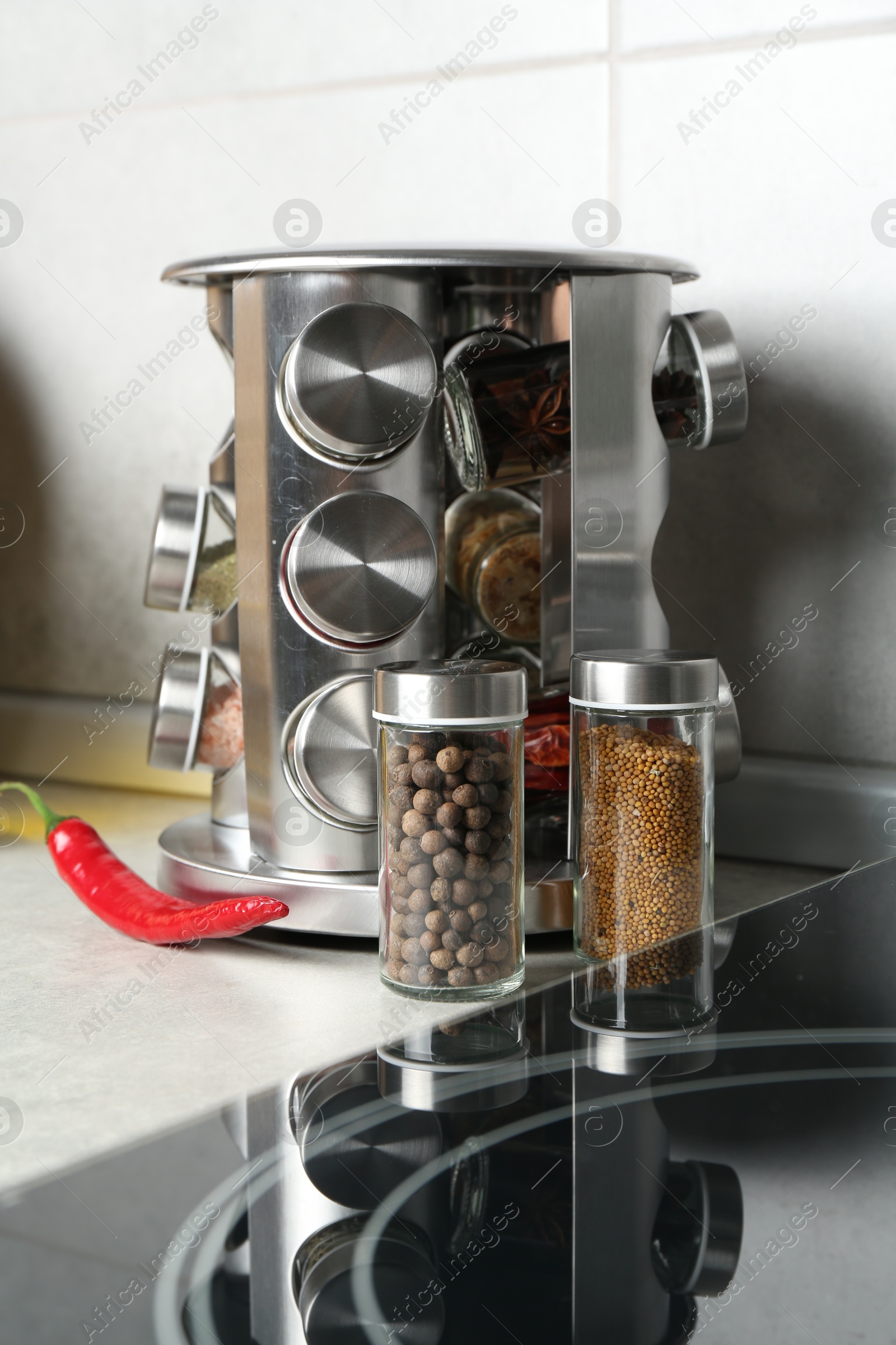 Set of different spices in glass jars on light grey table in kitchen Photo of Set of different spices in glass jars on light grey table in kitchen