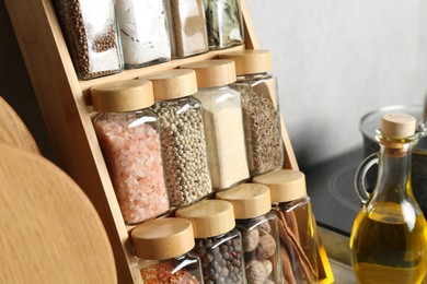 Photo of Set of different spices in glass jars and oil on table in kitchen, closeup