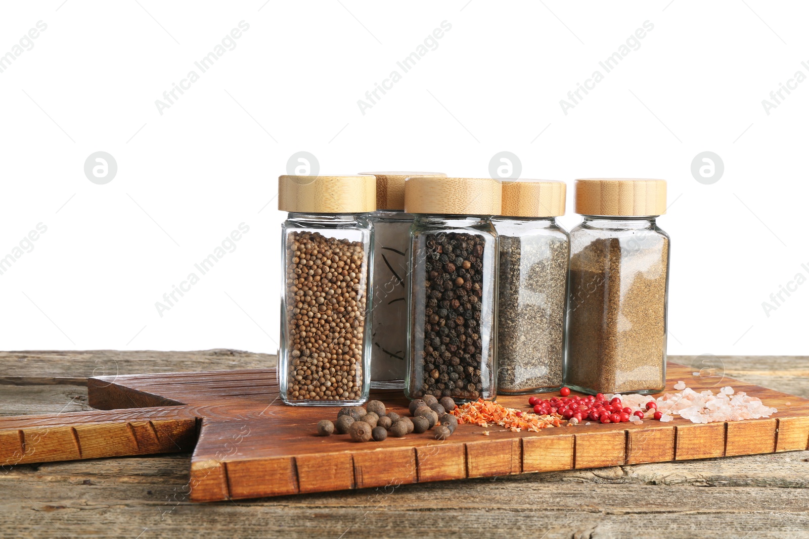 Photo of Many different aromatic spices in glass jars on wooden table against white background