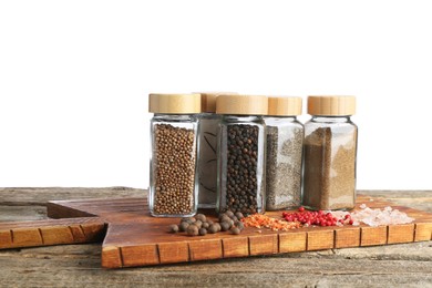 Photo of Many different aromatic spices in glass jars on wooden table against white background