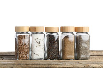 Photo of Many different aromatic spices in glass jars on wooden table against white background