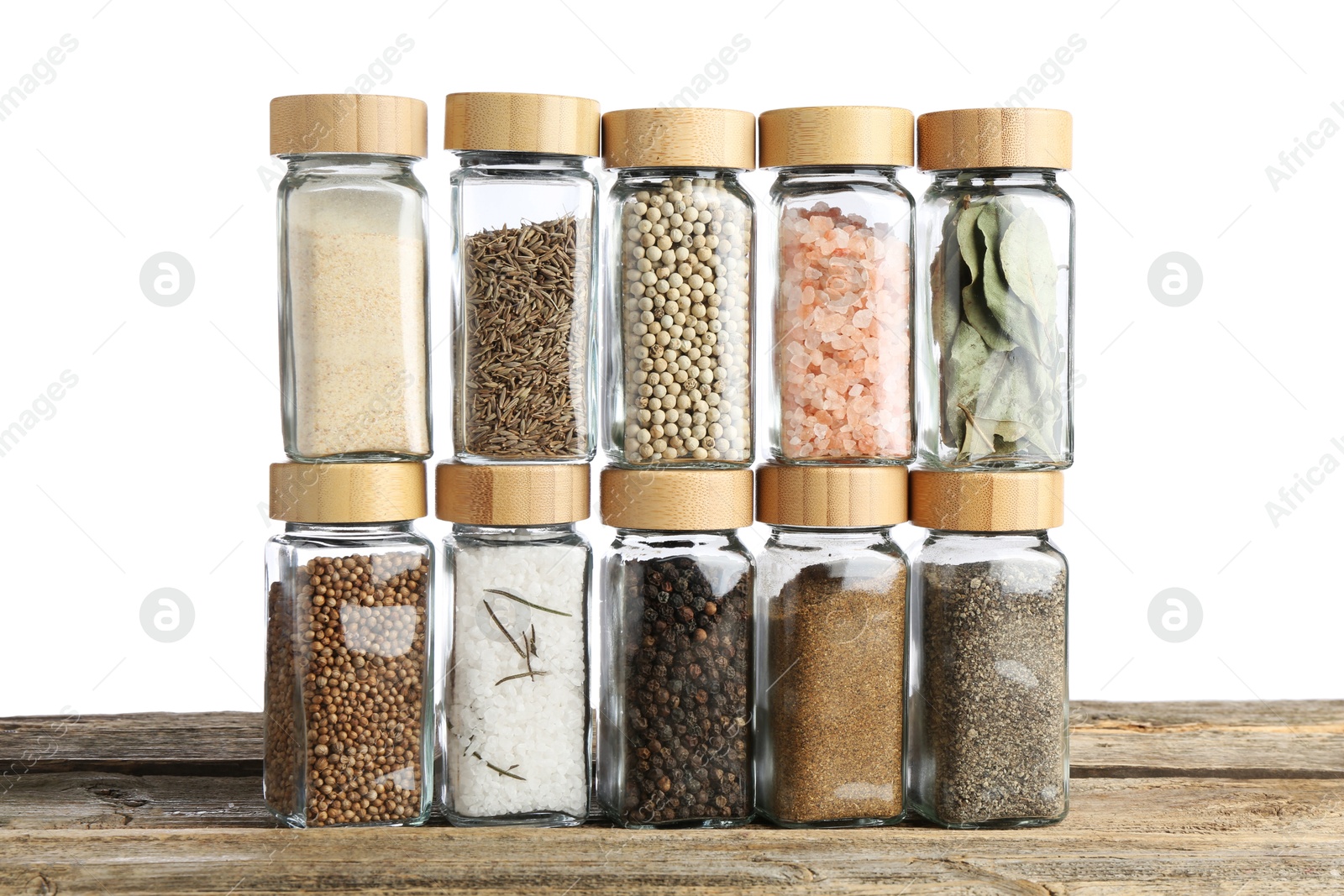 Photo of Many different aromatic spices in glass jars on wooden table against white background
