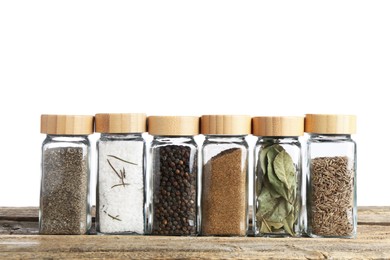 Photo of Many different aromatic spices in glass jars on wooden table against white background