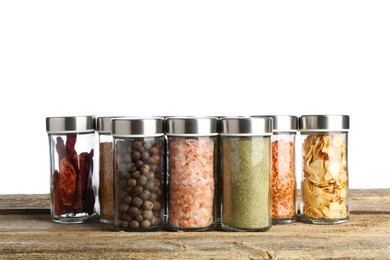 Photo of Many different aromatic spices in glass jars on wooden table against white background