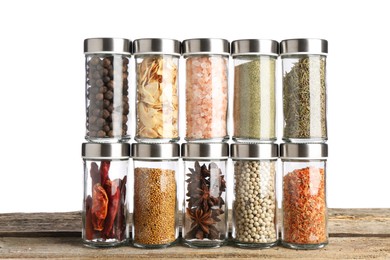 Photo of Many different aromatic spices in glass jars on wooden table against white background