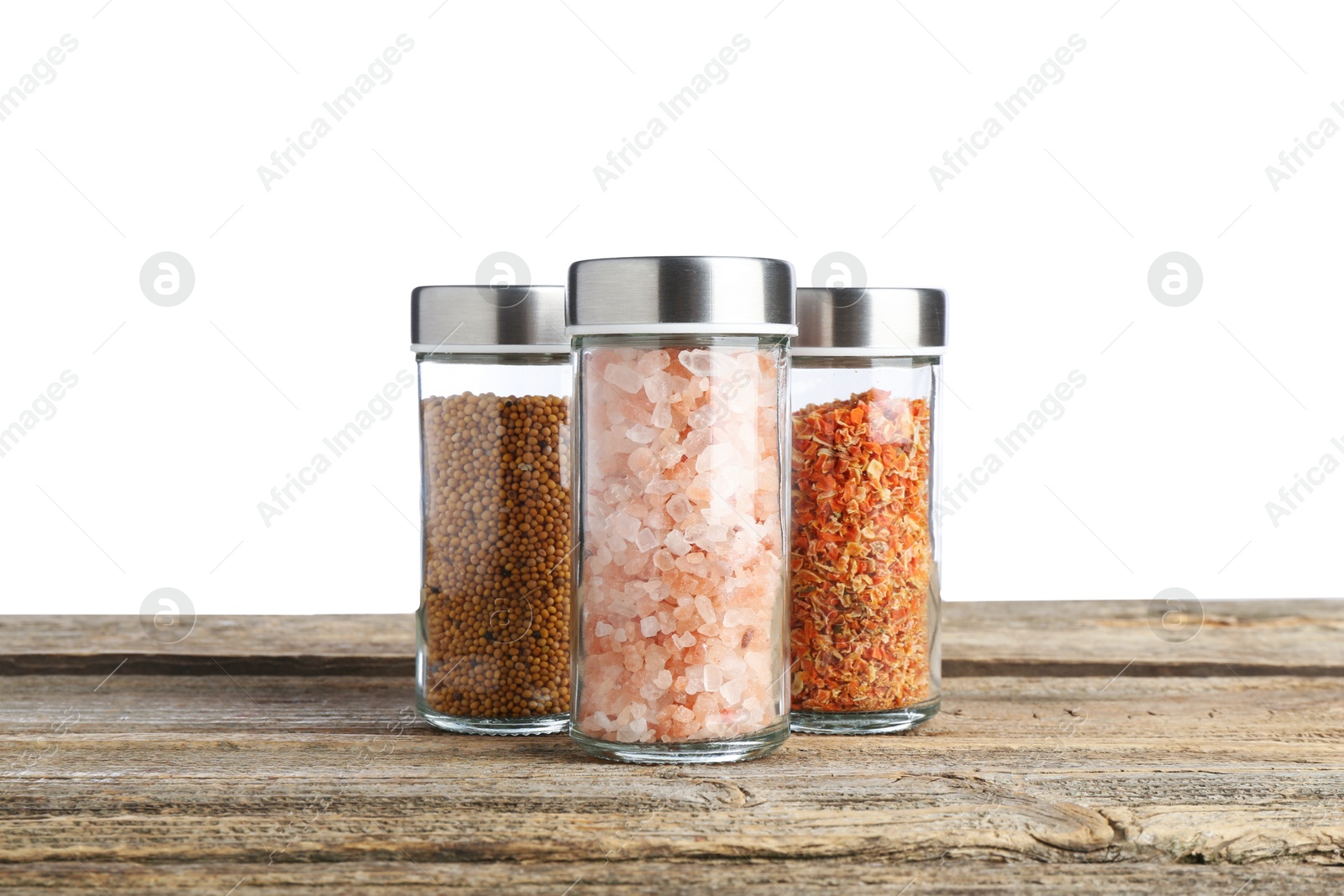 Photo of Many different aromatic spices in glass jars on wooden table against white background