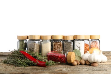 Photo of Many different spices and glass jars on wooden table against white background