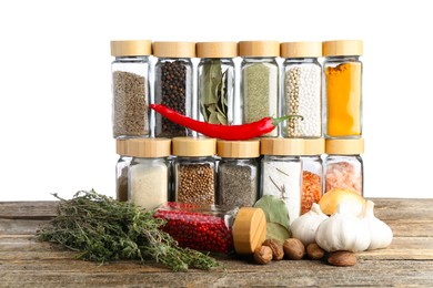 Photo of Many different spices and glass jars on wooden table against white background