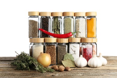Photo of Many different spices and glass jars on wooden table against white background