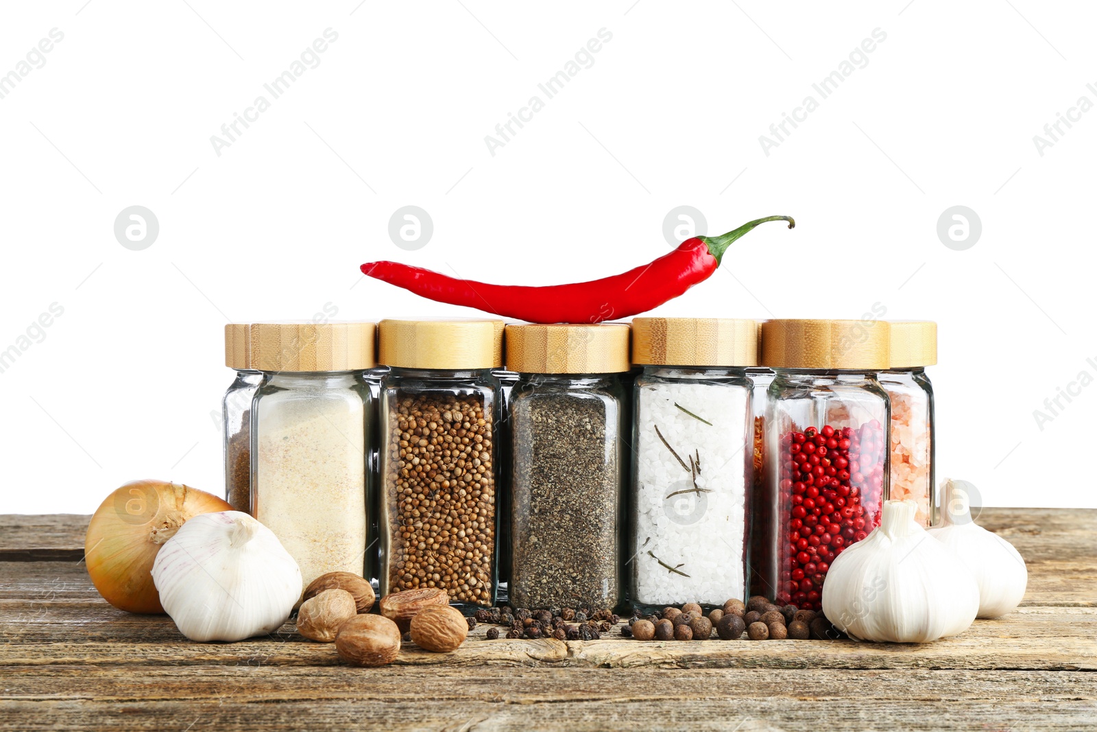 Photo of Many different spices and glass jars on wooden table against white background