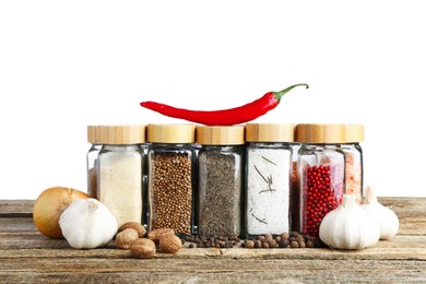 Photo of Many different spices and glass jars on wooden table against white background