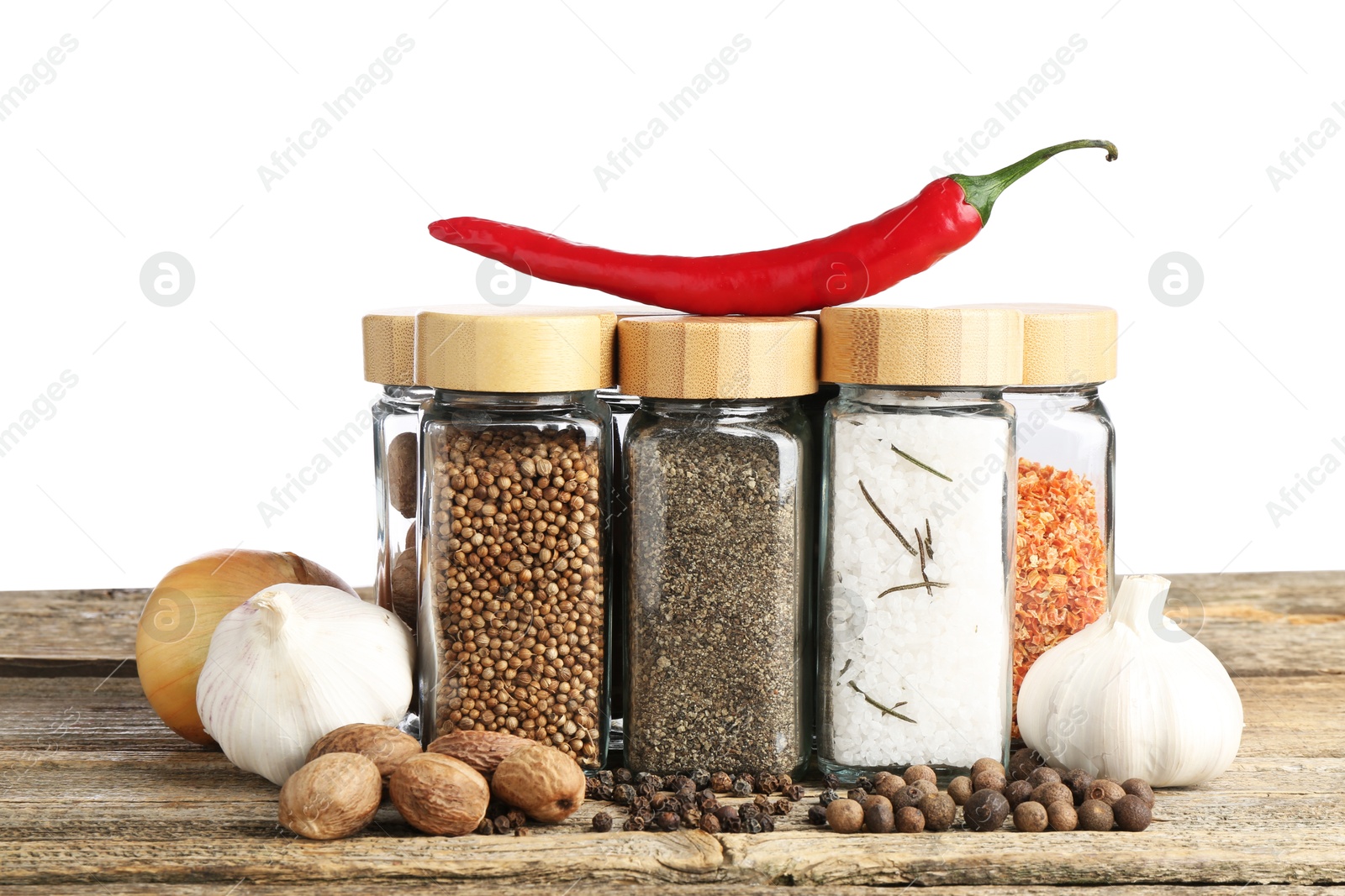 Photo of Many different spices and glass jars on wooden table against white background