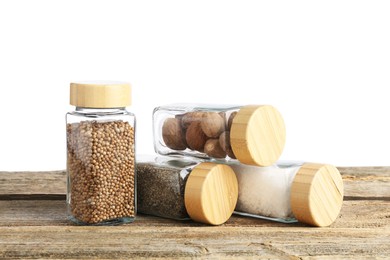 Photo of Many different aromatic spices in glass jars on wooden table against white background
