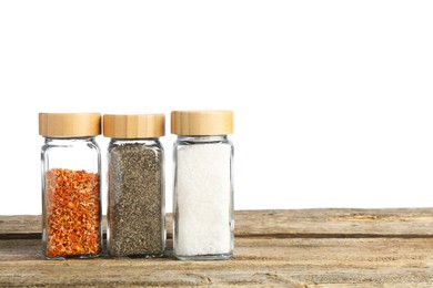 Photo of Many different aromatic spices in glass jars on wooden table against white background. Space for text