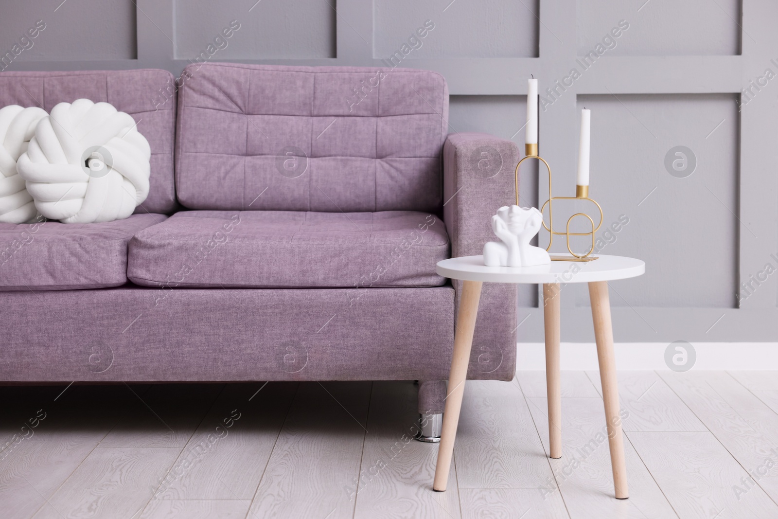 Photo of Comfortable sofa with cushions and decor on side table indoors