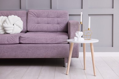 Photo of Comfortable sofa with cushions and decor on side table indoors