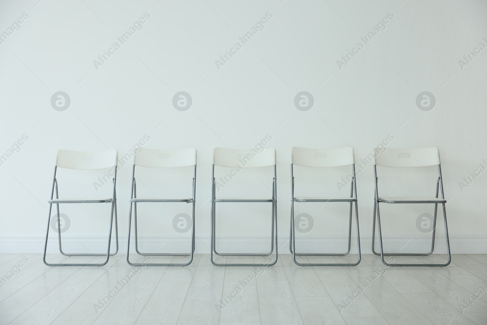 Photo of Many chairs near white wall in room