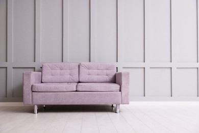 Photo of Comfortable violet sofa near gray wall in room