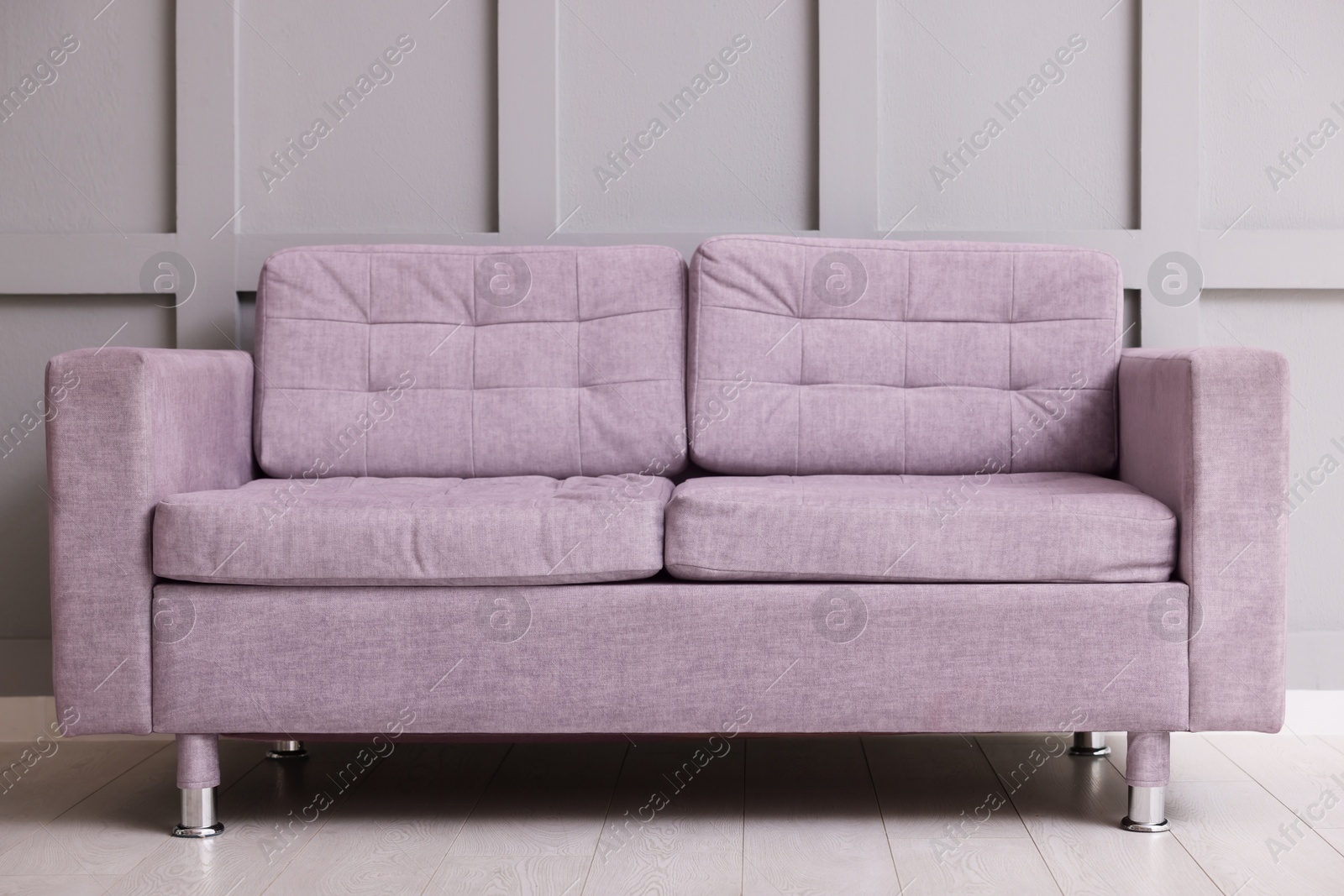 Photo of Comfortable violet sofa near gray wall in room