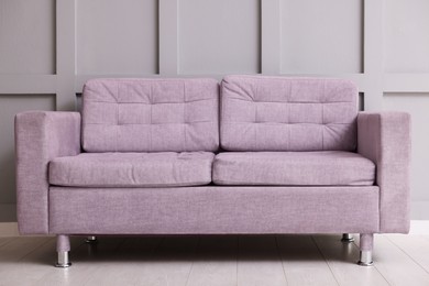 Photo of Comfortable violet sofa near gray wall in room