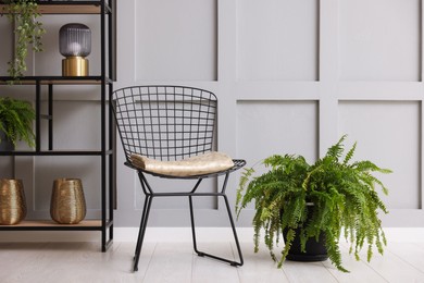 Photo of Stylish metal chair and rack with different decor indoors. Interior design