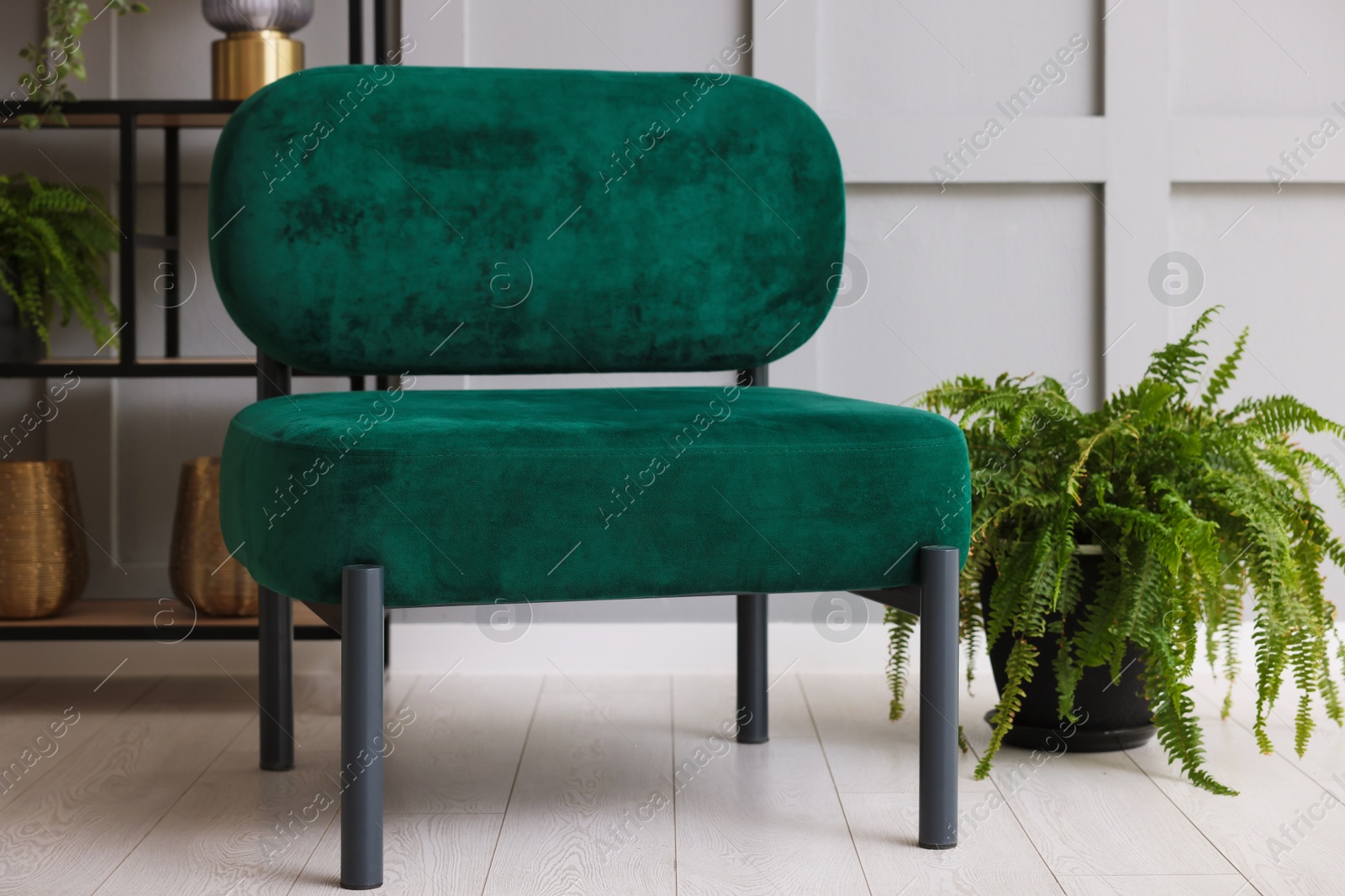Photo of Stylish armchair and rack with different decor near gray wall in room. Interior design