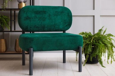 Photo of Stylish armchair and rack with different decor near gray wall in room. Interior design