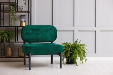 Photo of Stylish armchair and rack with different decor near gray wall in room. Interior design