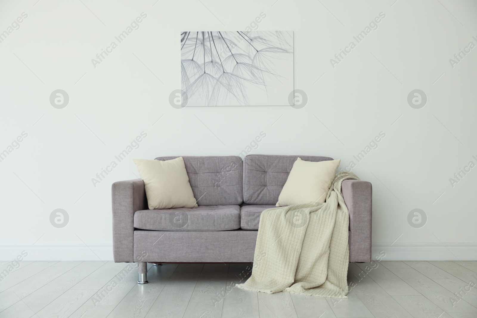 Photo of Comfortable gray sofa with blanket and cushions in room. Interior design