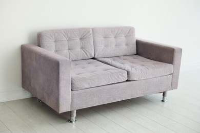 Photo of Comfortable gray sofa near white wall in room