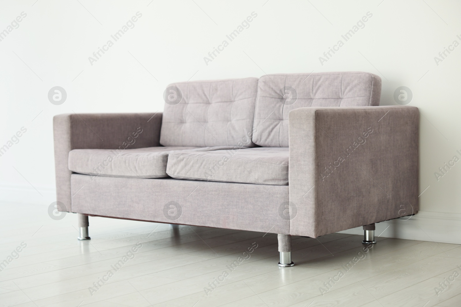 Photo of Comfortable gray sofa near white wall in room