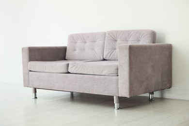 Photo of Comfortable gray sofa near white wall in room