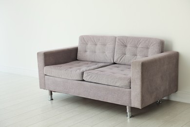 Photo of Comfortable gray sofa near white wall in room