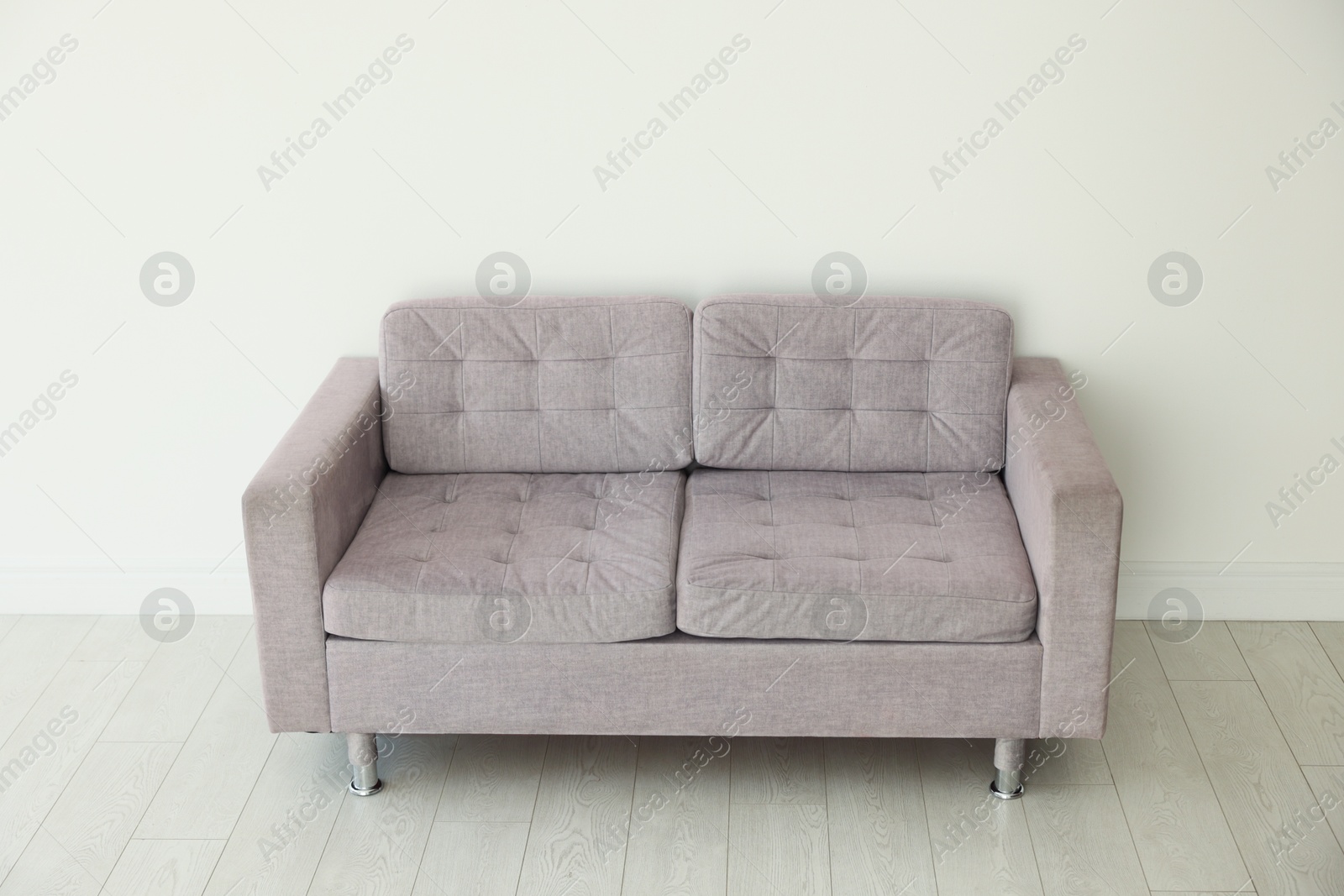 Photo of Comfortable gray sofa near white wall in room
