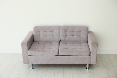 Photo of Comfortable gray sofa near white wall in room