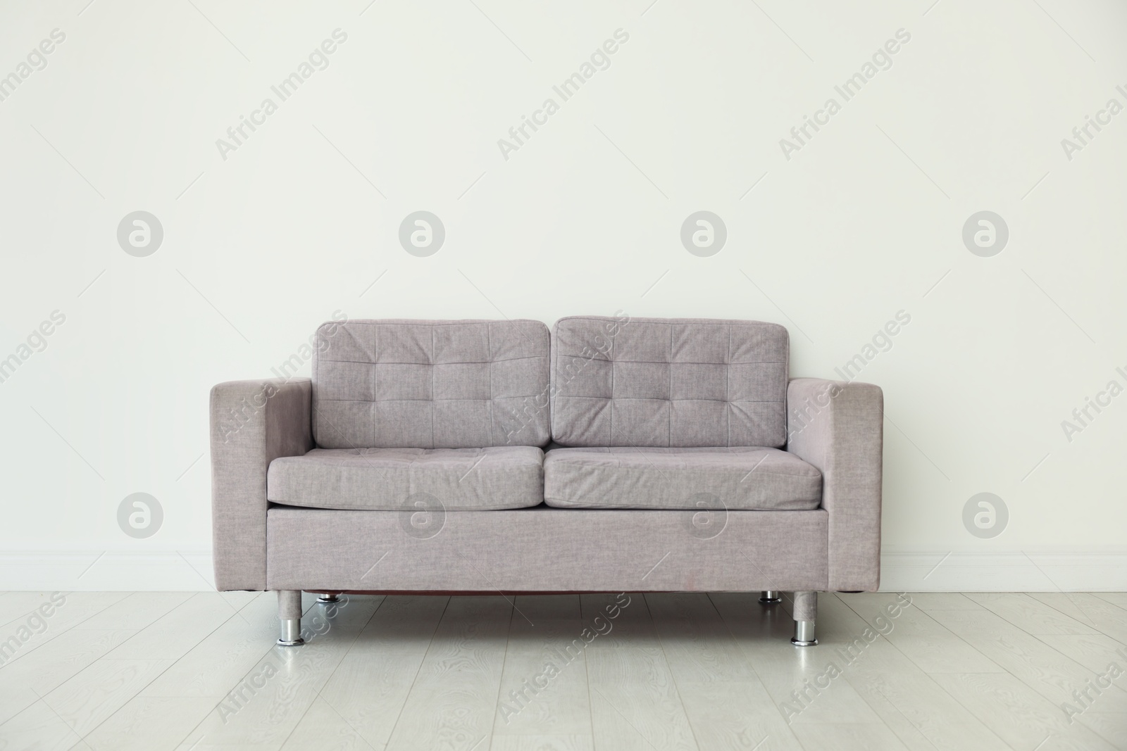 Photo of Comfortable gray sofa near white wall in room
