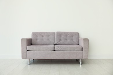 Photo of Comfortable gray sofa near white wall in room
