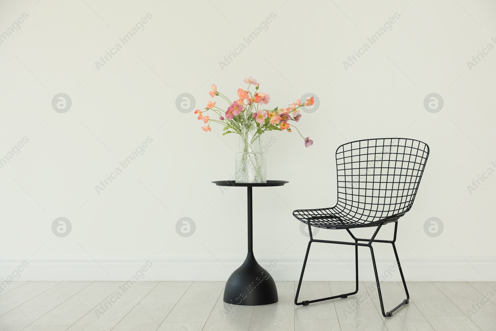 Photo of Stylish metal chair and beautiful flowers in vase on black table indoors, space for text