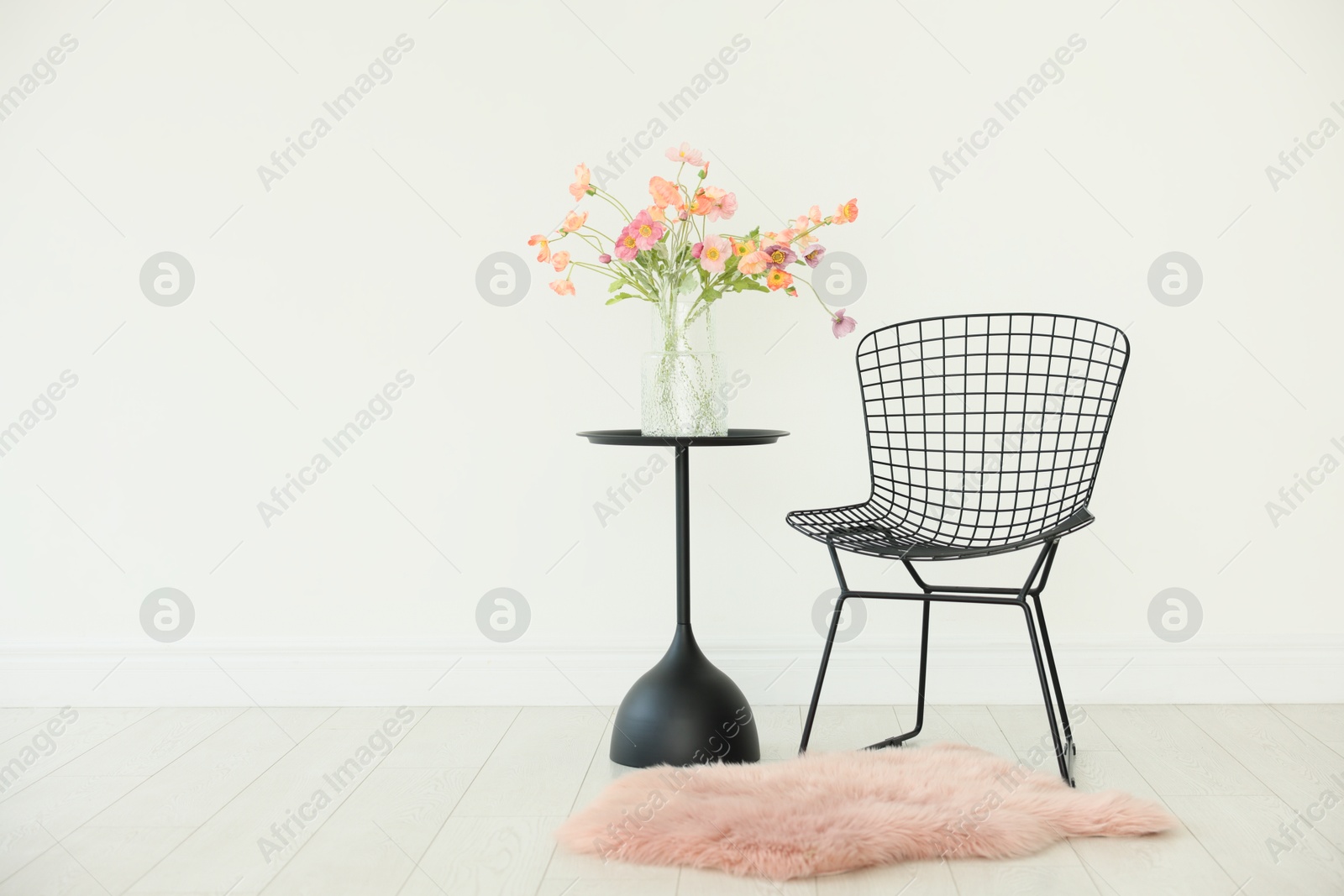Stylish metal chair and beautiful flowers in vase on black table indoors, space for text Photo of Stylish metal chair and beautiful flowers in vase on black table indoors, space for text