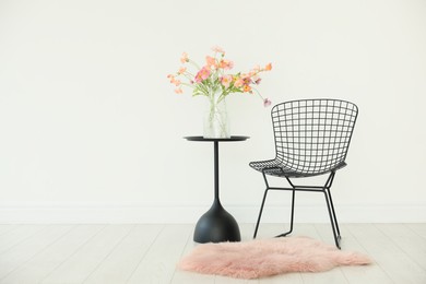 Photo of Stylish metal chair and beautiful flowers in vase on black table indoors, space for text
