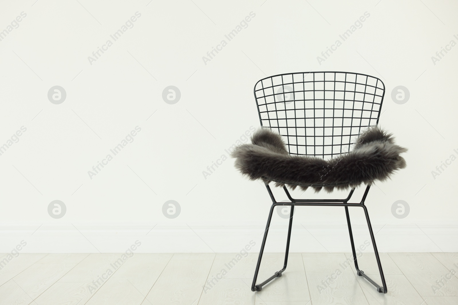Stylish metal chair and fluffy blanket indoors, space for text Photo of Stylish metal chair and fluffy blanket indoors, space for text