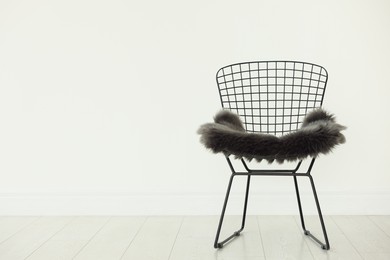 Photo of Stylish metal chair and fluffy blanket indoors, space for text